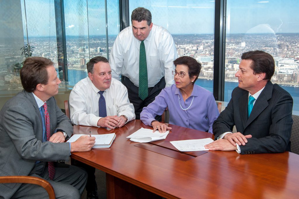 five executives meet in a conference room with an expansive view of the city